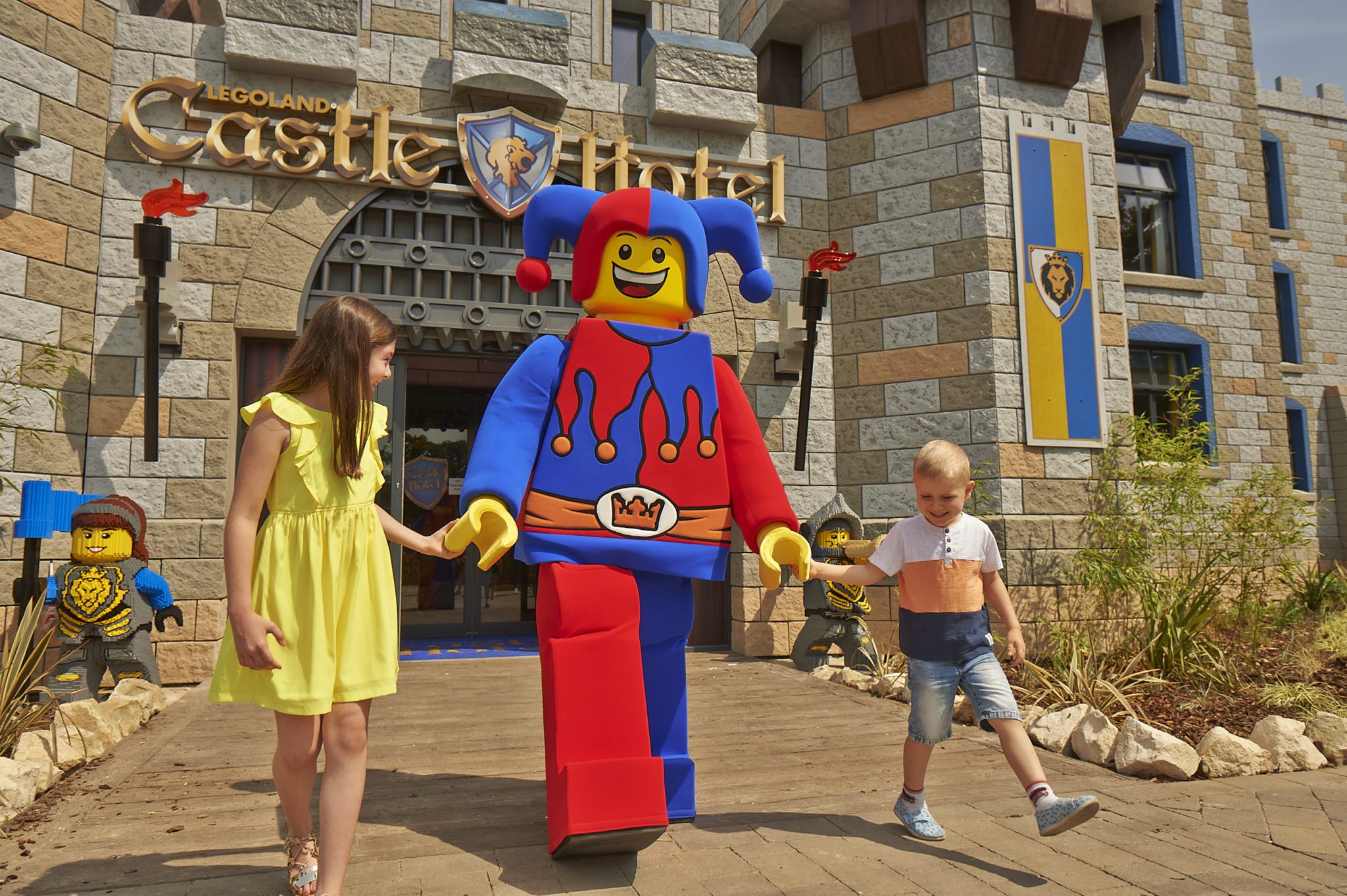A LEGO character outside the castle hotel entrance with 2 people