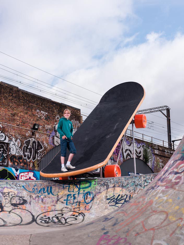 A model of a large skateboard stood at an angle with a person stood on it