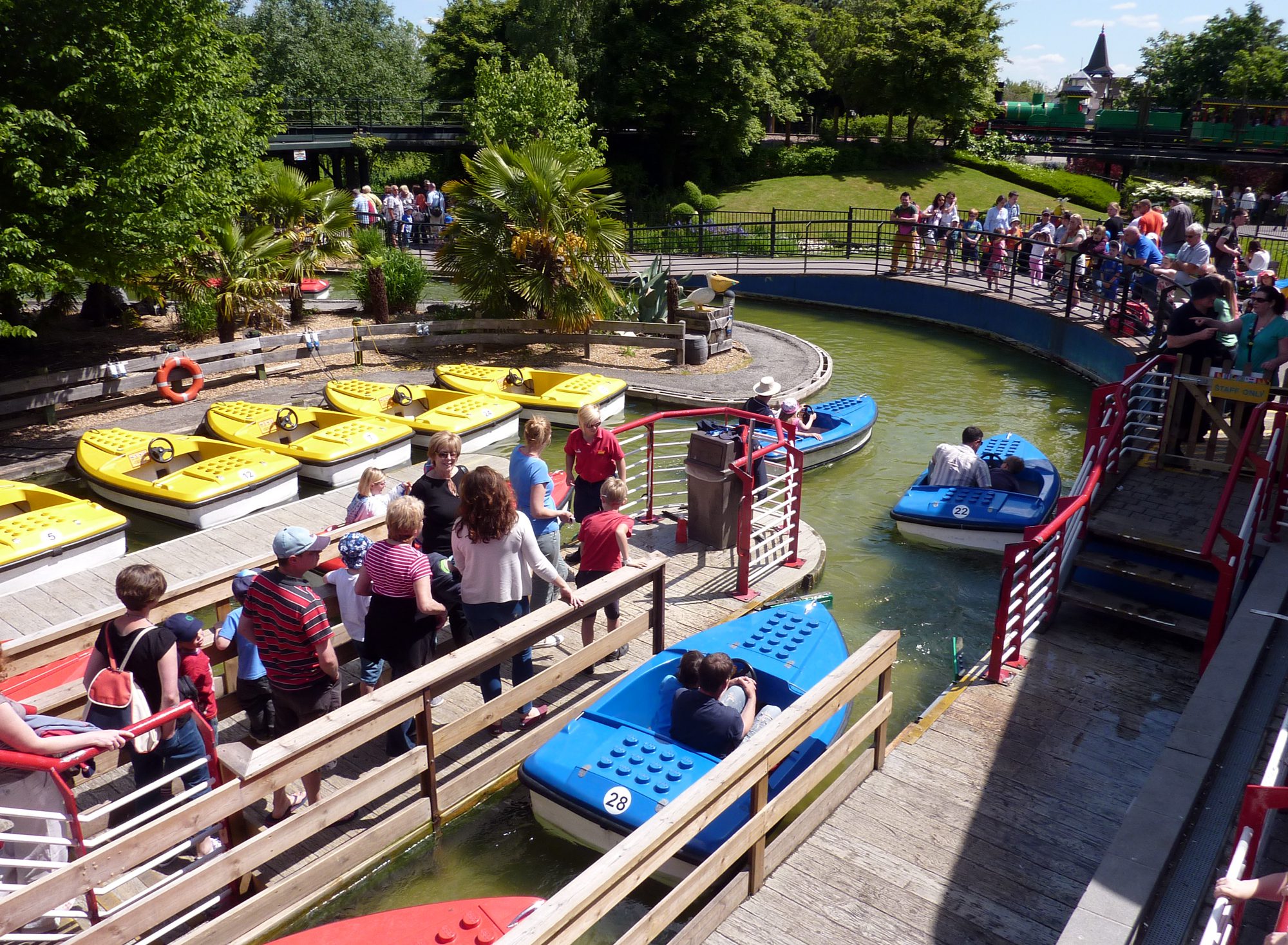 A water LEGO themed station area with people and blue and yellow boats