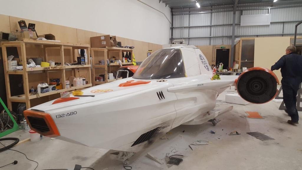 A white and orange police ship in a workshop