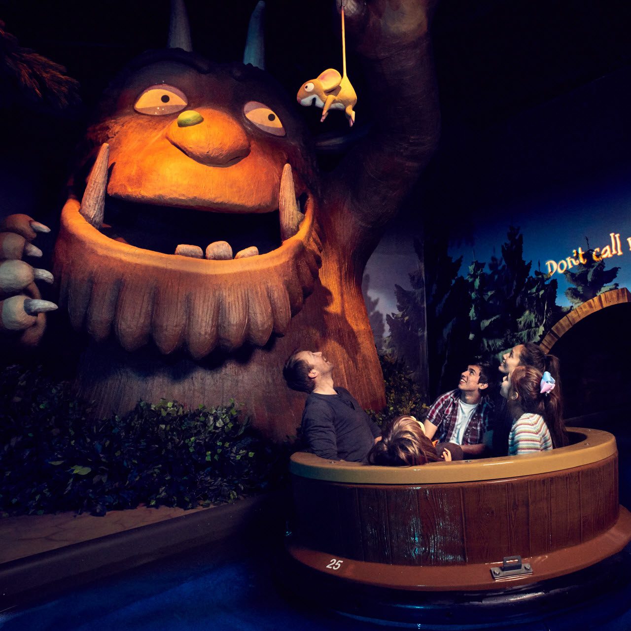 The inside of the Gruffalo ride with 5 people in a boat with a large Gruffalo sculpture to the left