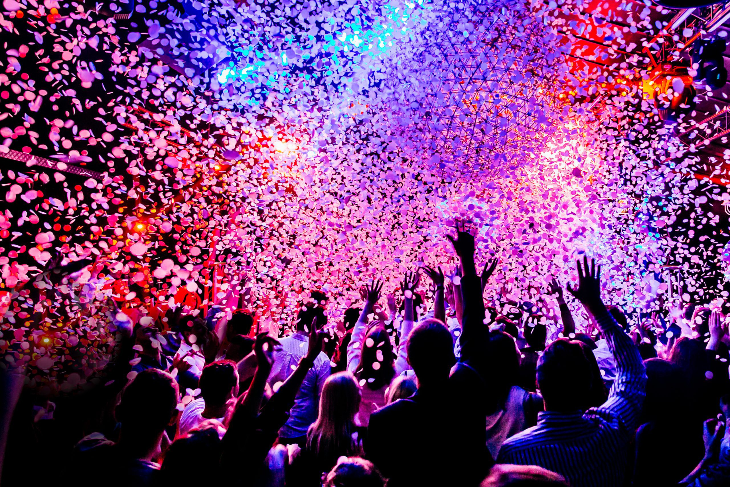 People in a crowd with pink and purple confetti falling down