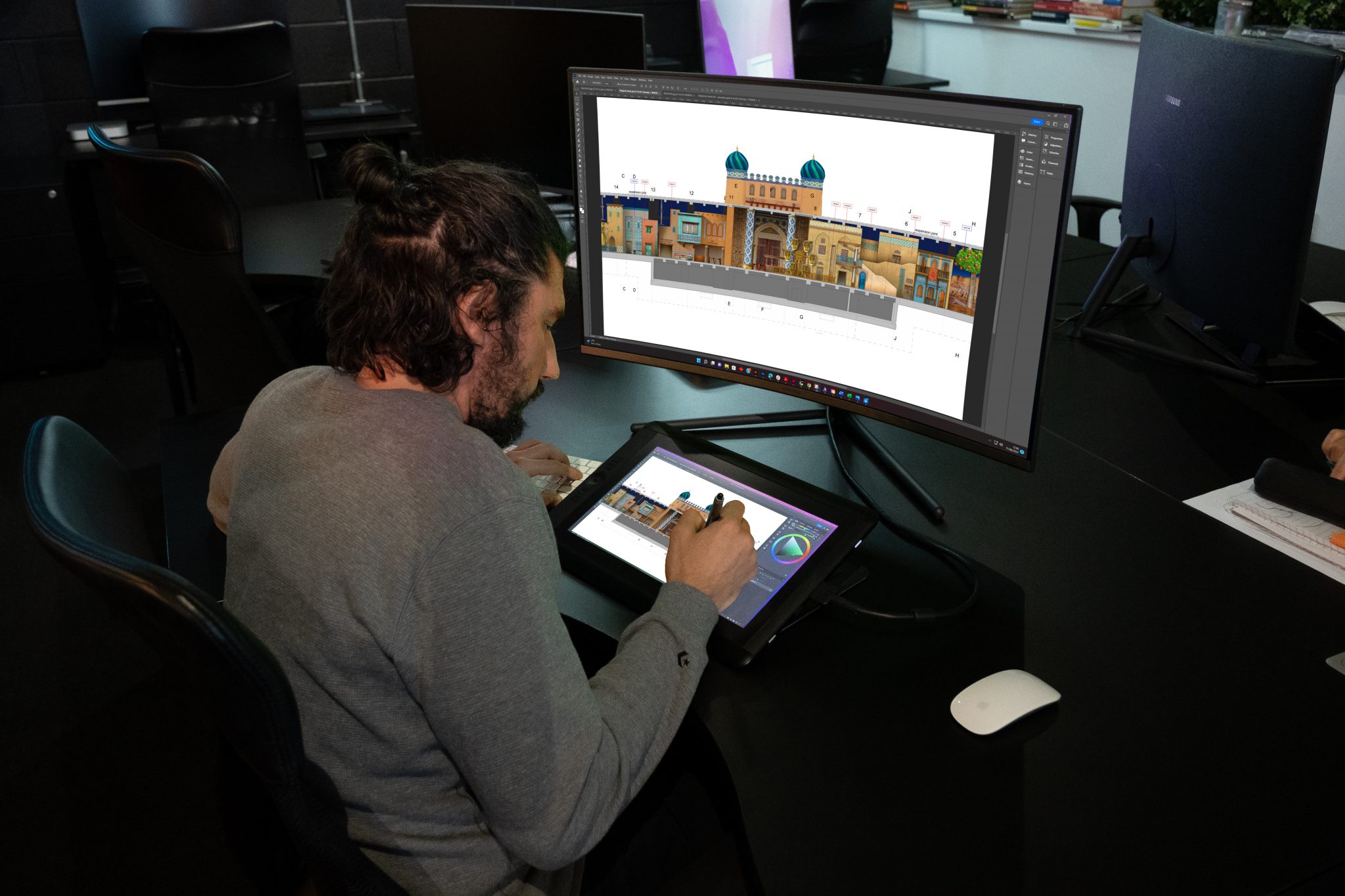 A person drawing a concept image on a tablet of a large building while it's being projected onto a computer screen