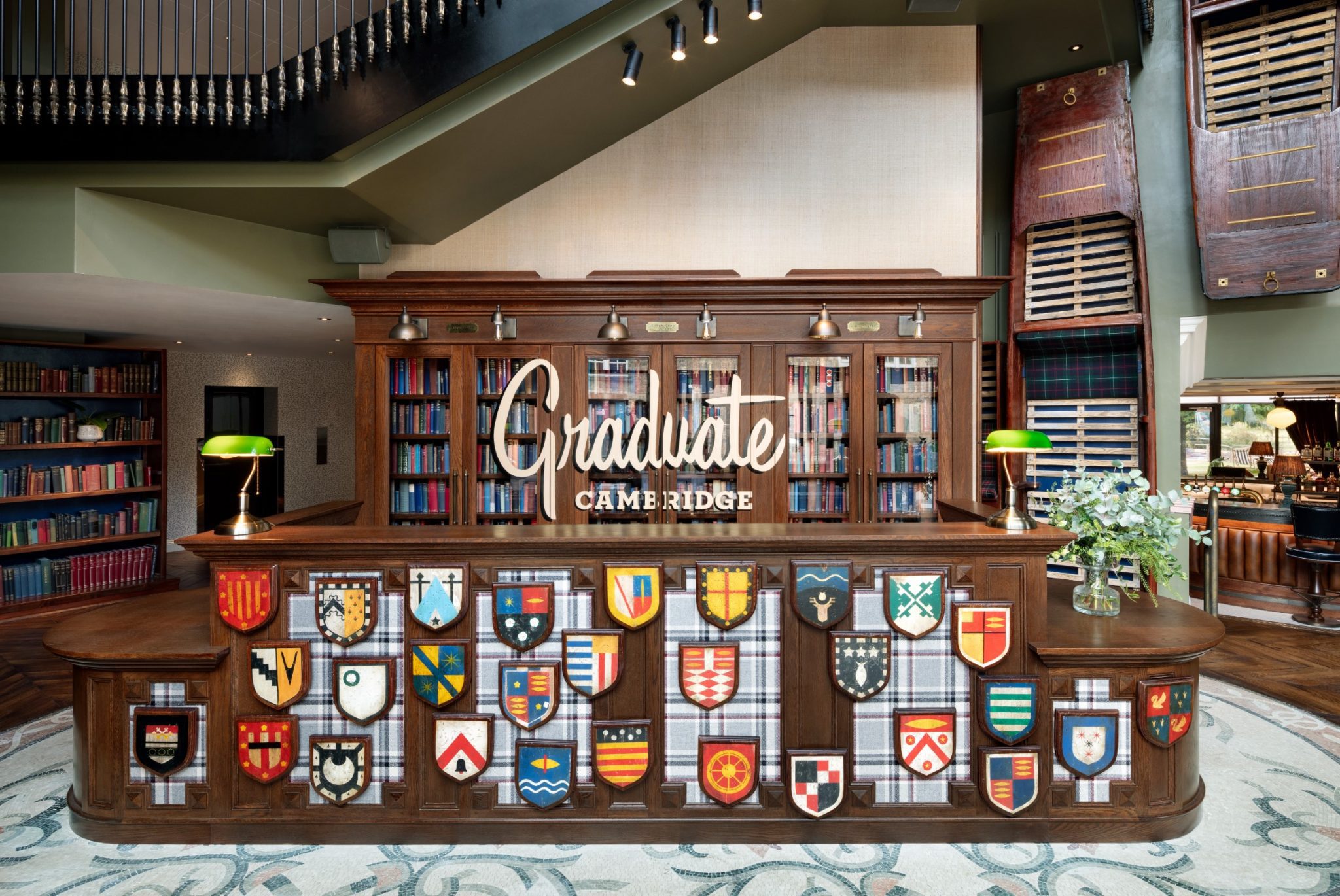 A desk with shields in front and a sign above that says 'Graduate Cambridge'