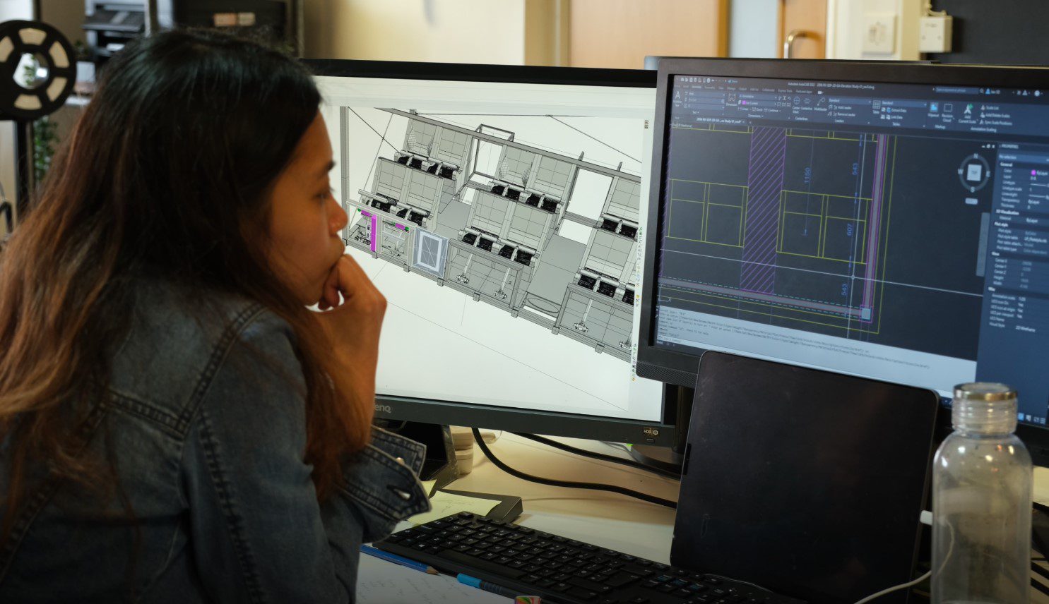 A person looking at 2 computer monitors creating concept art of a building